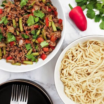 Overhead shot of a dish of Thai pork mince stir fry with a dish of noodles.