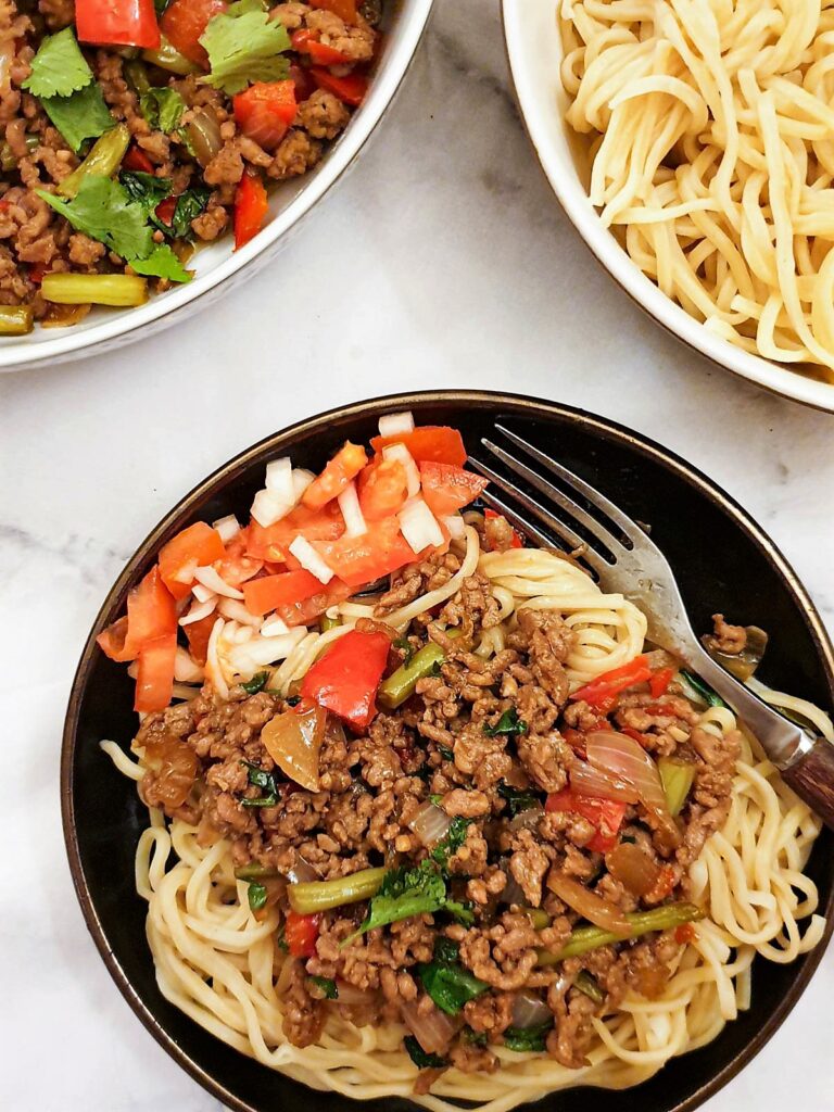 Thai pork mince stir fry on a plate of noodles.