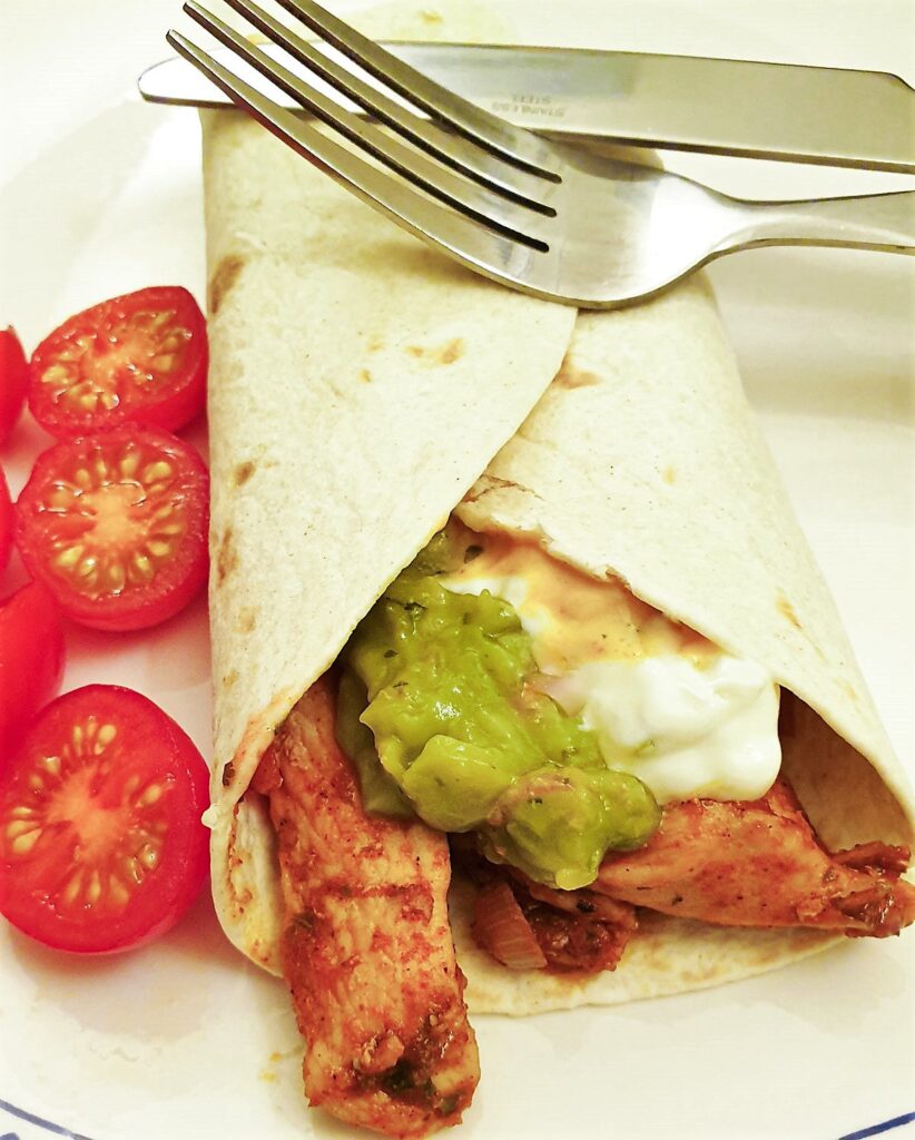 Strips of chicken and fajita toppings in a flour tortilla wrap.