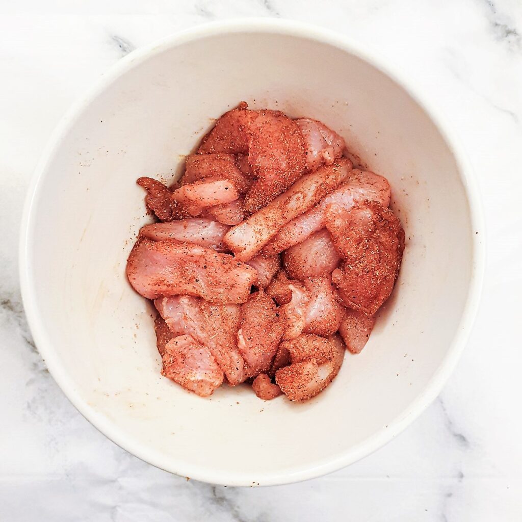 Chicken strips coated with fajita spices in a bowl.
