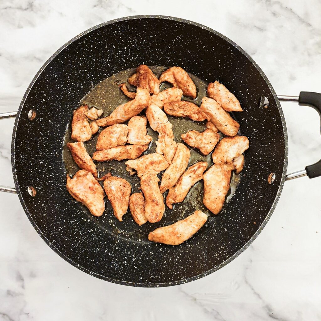 Strips of chicken frying in a pan.