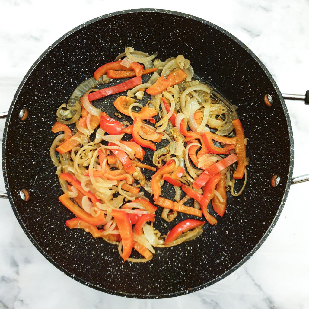 Peppers and onions in a frying pan.