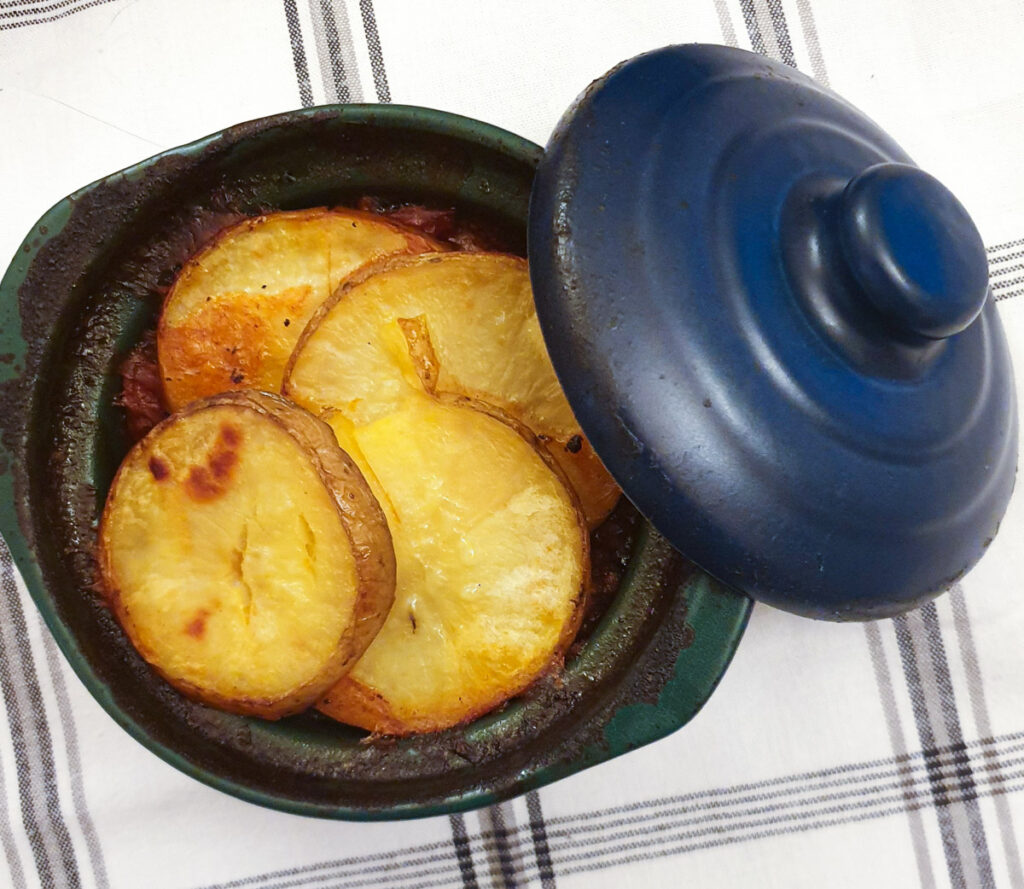 A small casserole dish of baked minced beef hotpot.