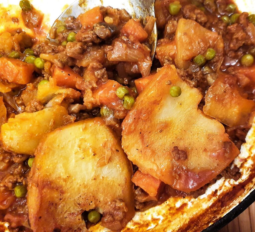 Closeup of minced beef and vegetables with sliced potatoes.