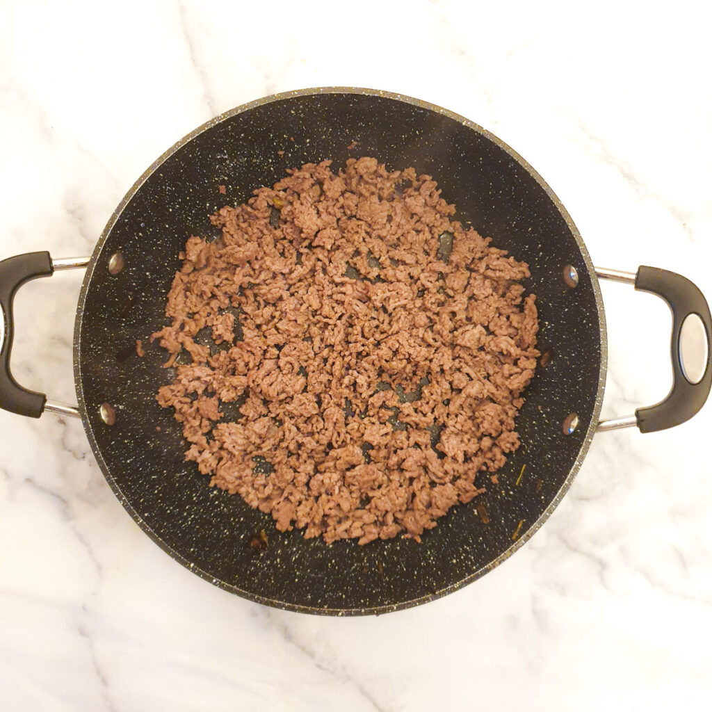 Minced beef being browned in a frying pan.