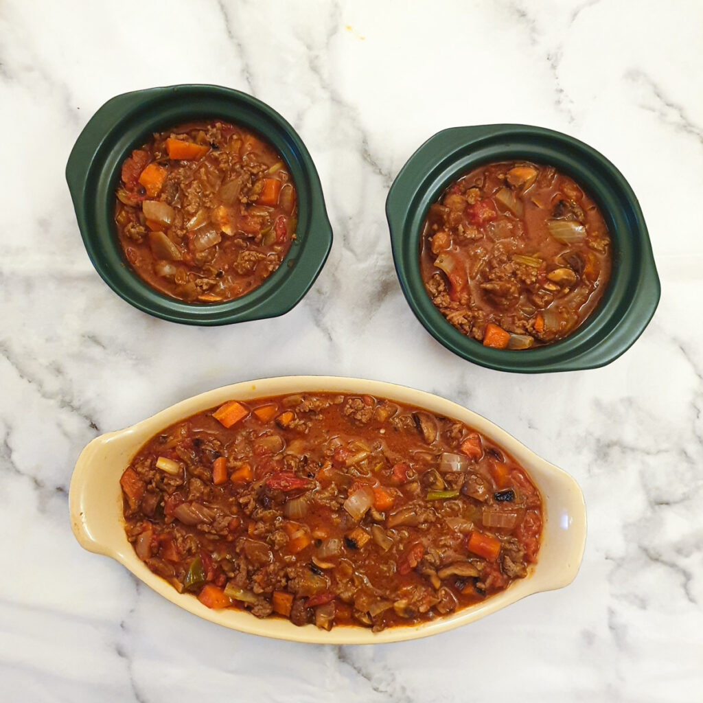 Minced beef mixture in one large and two small casserole dishes.