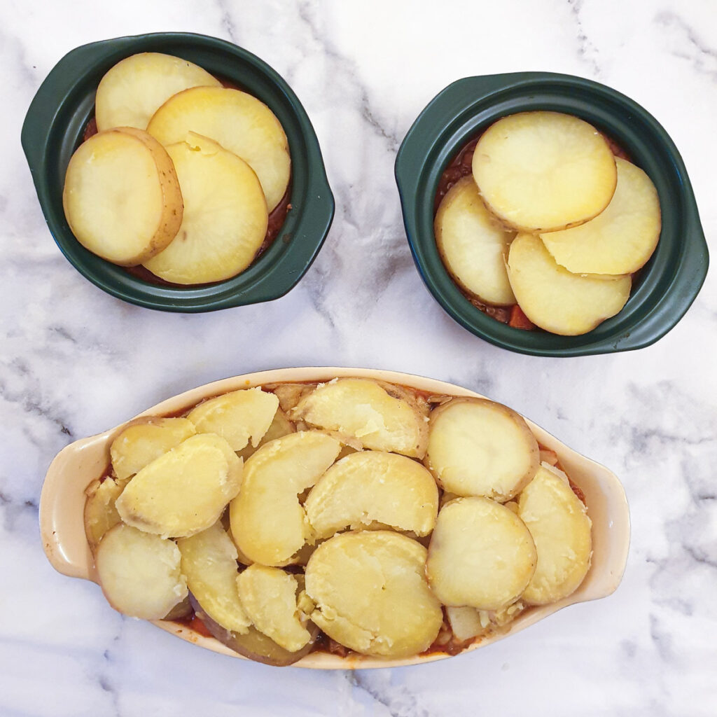 Sliced potatoes on top of the mince mixture, ready for the oven.