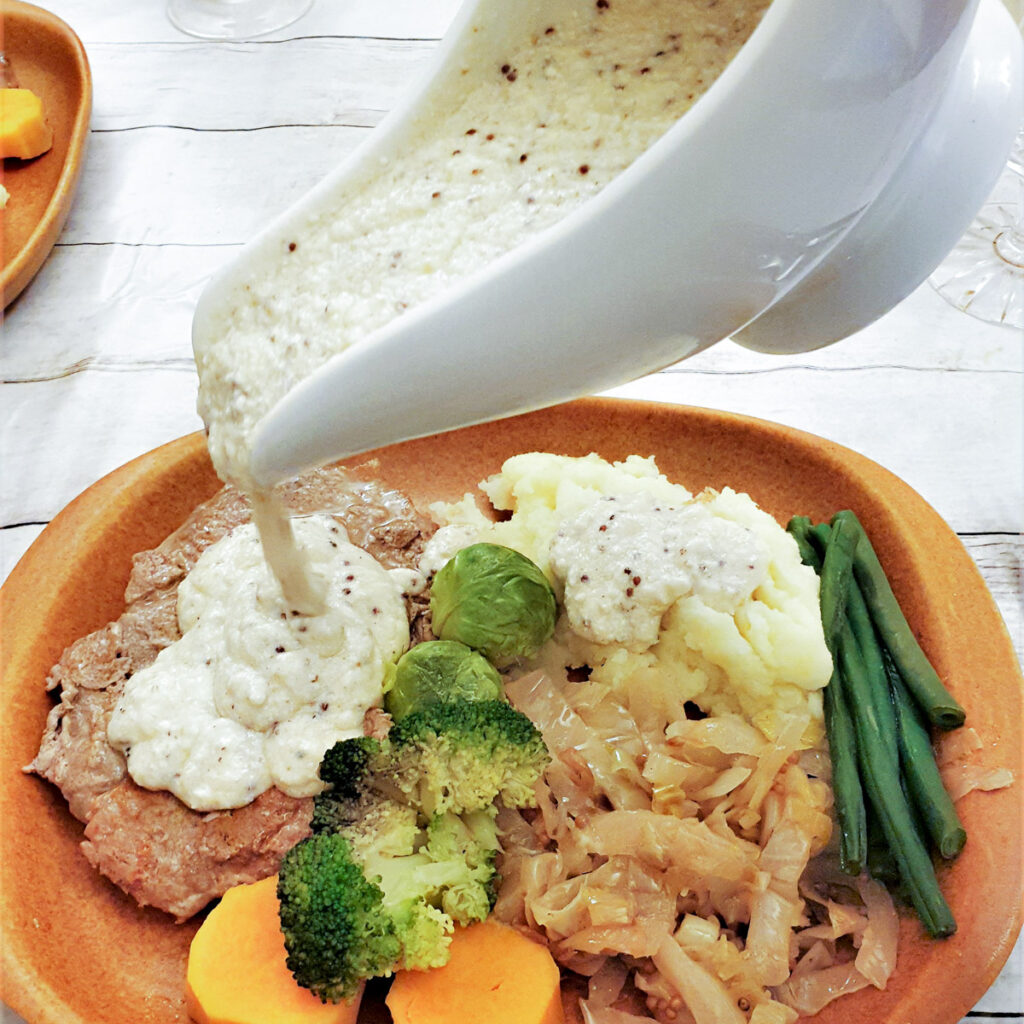 Honey mustard sauce being poured over a plate of food.