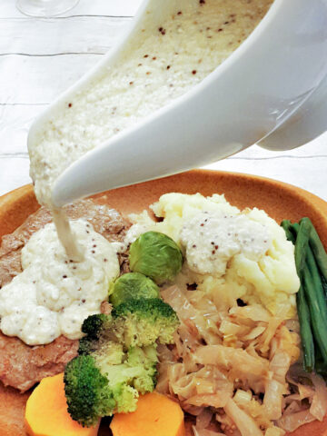 Honey mustard sauce being poured from a gravy boat.