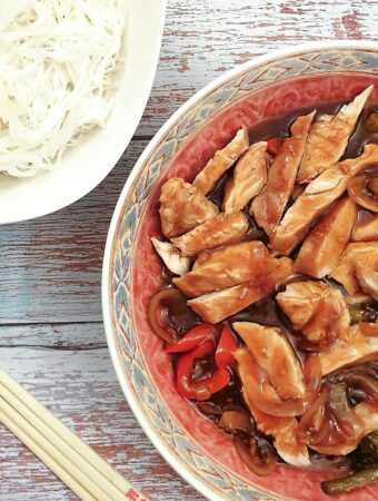 A serving dish of teriyaki chicken with a bowl of noodles.