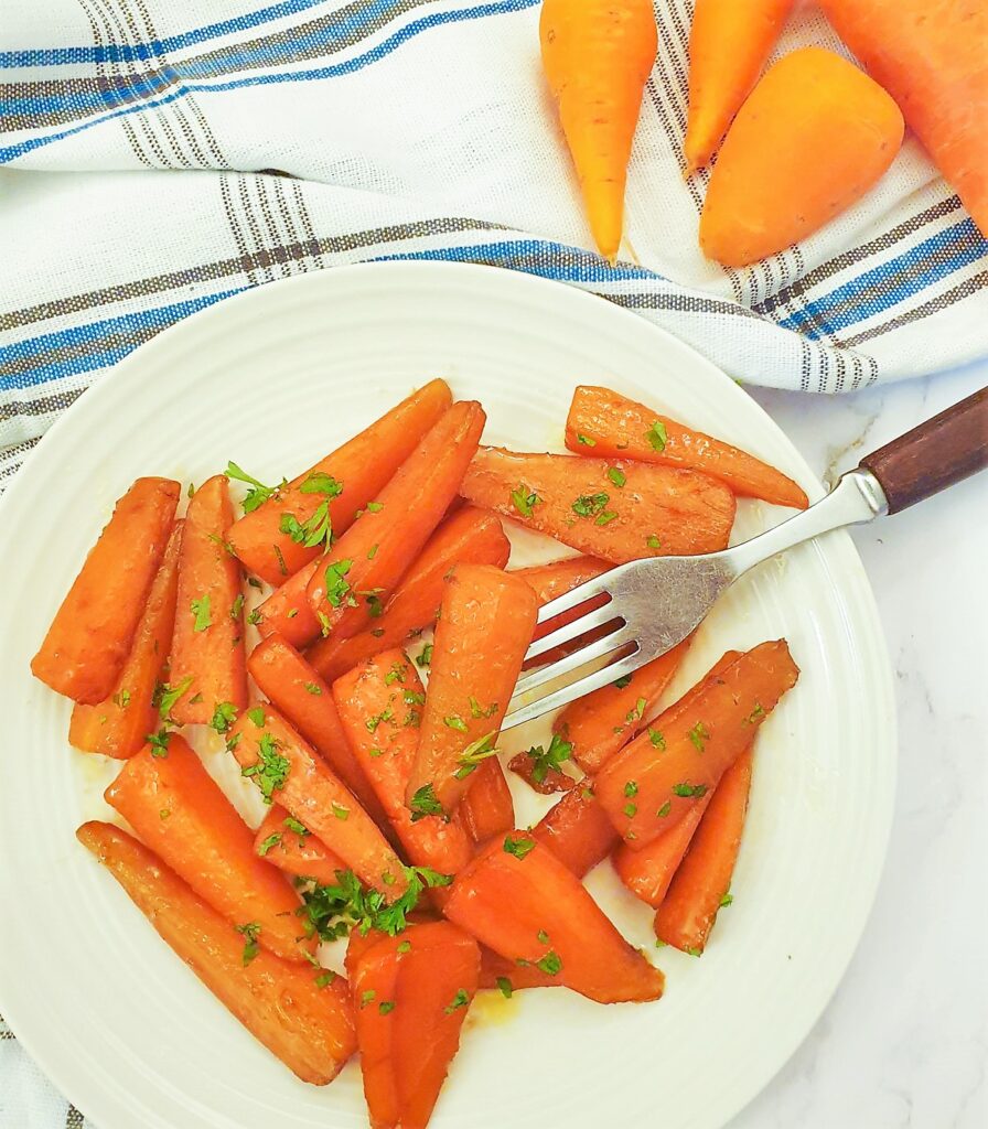 A plate of glazed carrots alongside some raw carrots.