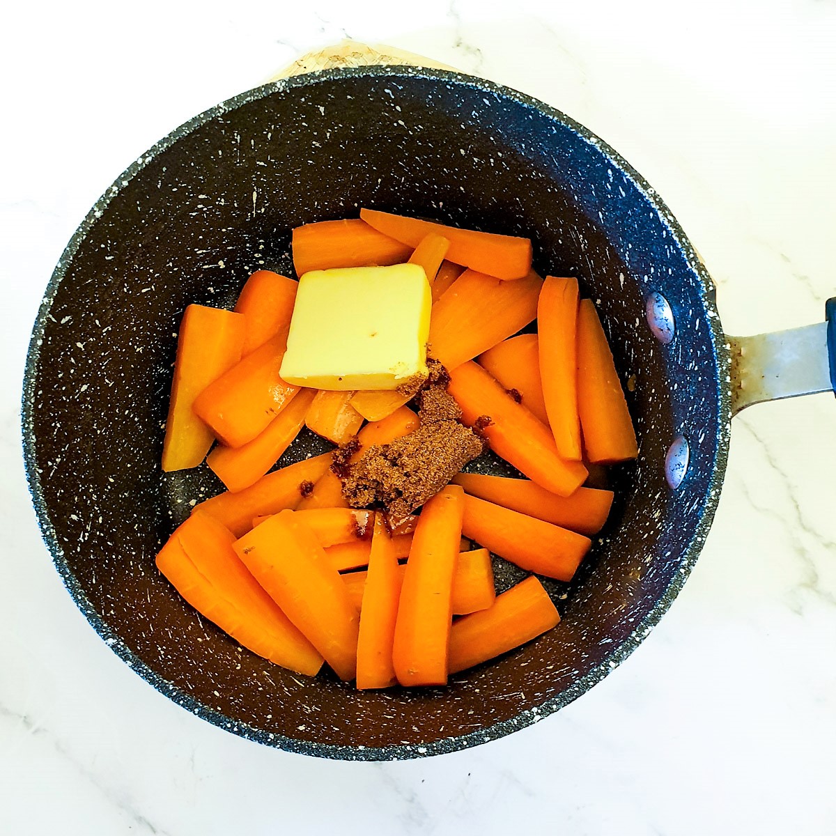 Par-boiled carrots in a pan with butter and brown sugar.