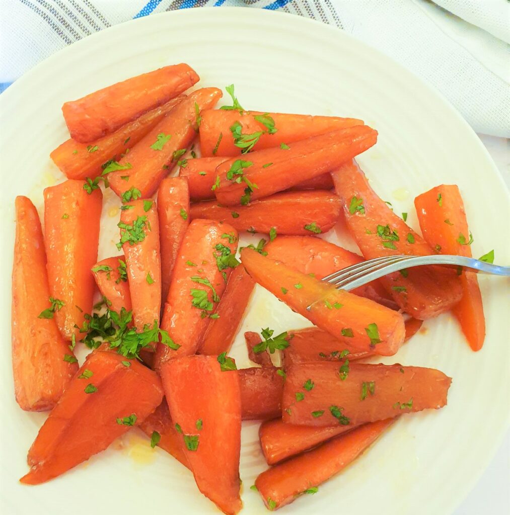 Glazed carrots on a plate with one carrot on a fork.