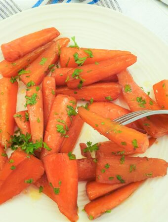 Glazed carrots on a plate with one carrot on a fork.