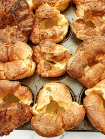 Perfectly risen Yorkshire puddings on a baking sheet.