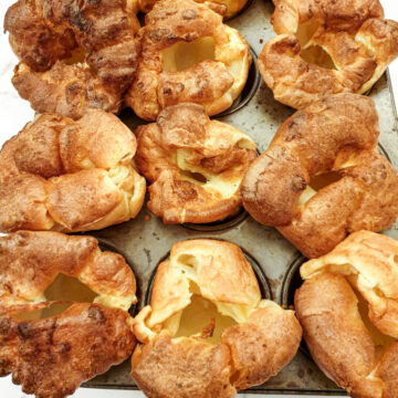 Perfectly risen Yorkshire puddings on a baking sheet.