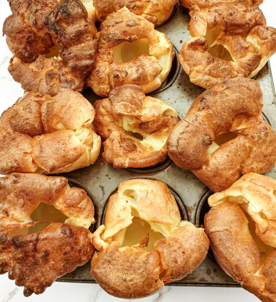 Perfectly risen Yorkshire puddings on a baking sheet.