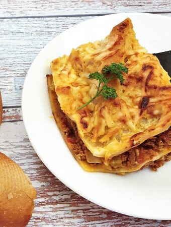A slice of lasagne being lifted onto a plate.