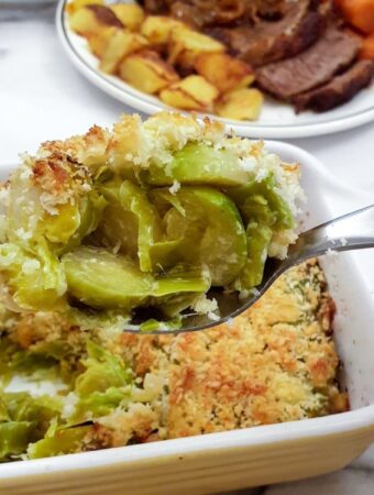 A spoonful of leek and brussels sprout bake being lifted from the serving dish.