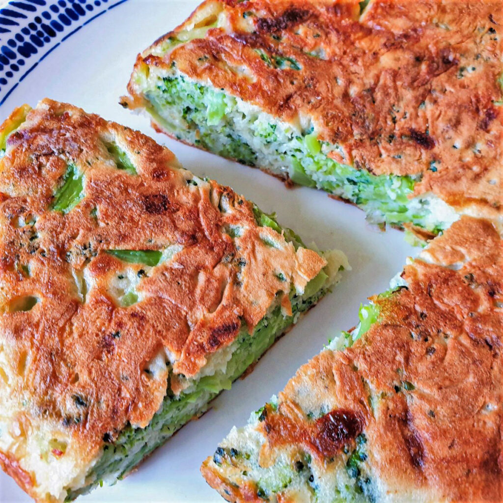 Overhead image of a broccoli and cheese tart with a slice offset.