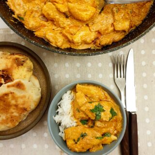 A dish of butter chicken on a bed of white rice.