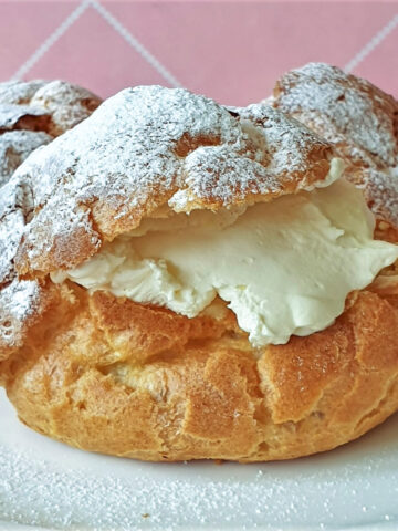 3 cream puffs filled with cream on a plate.