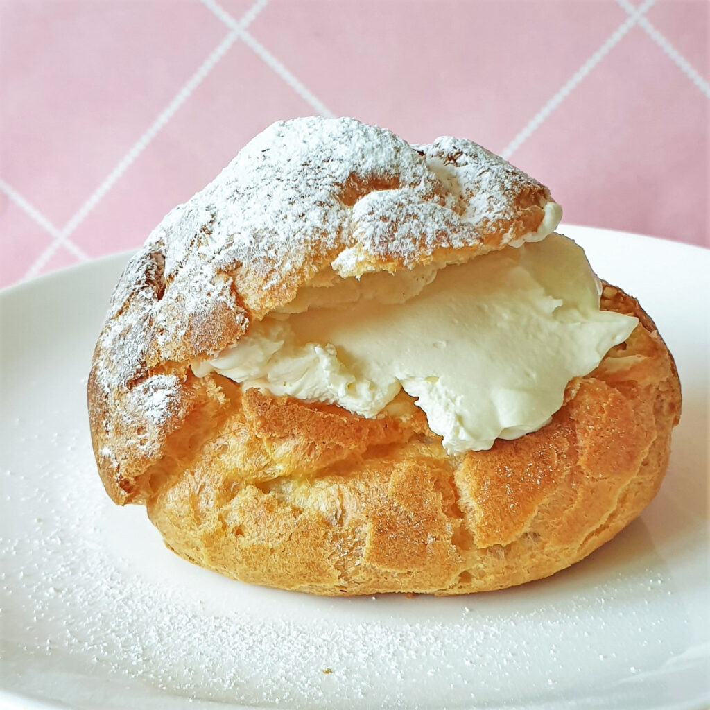 A cream puff filled with cream on a plate.