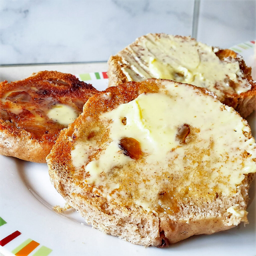 A toasted hot cross bun spread with butter.