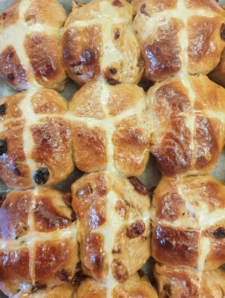 A close up of hot cross buns on a baking tray.