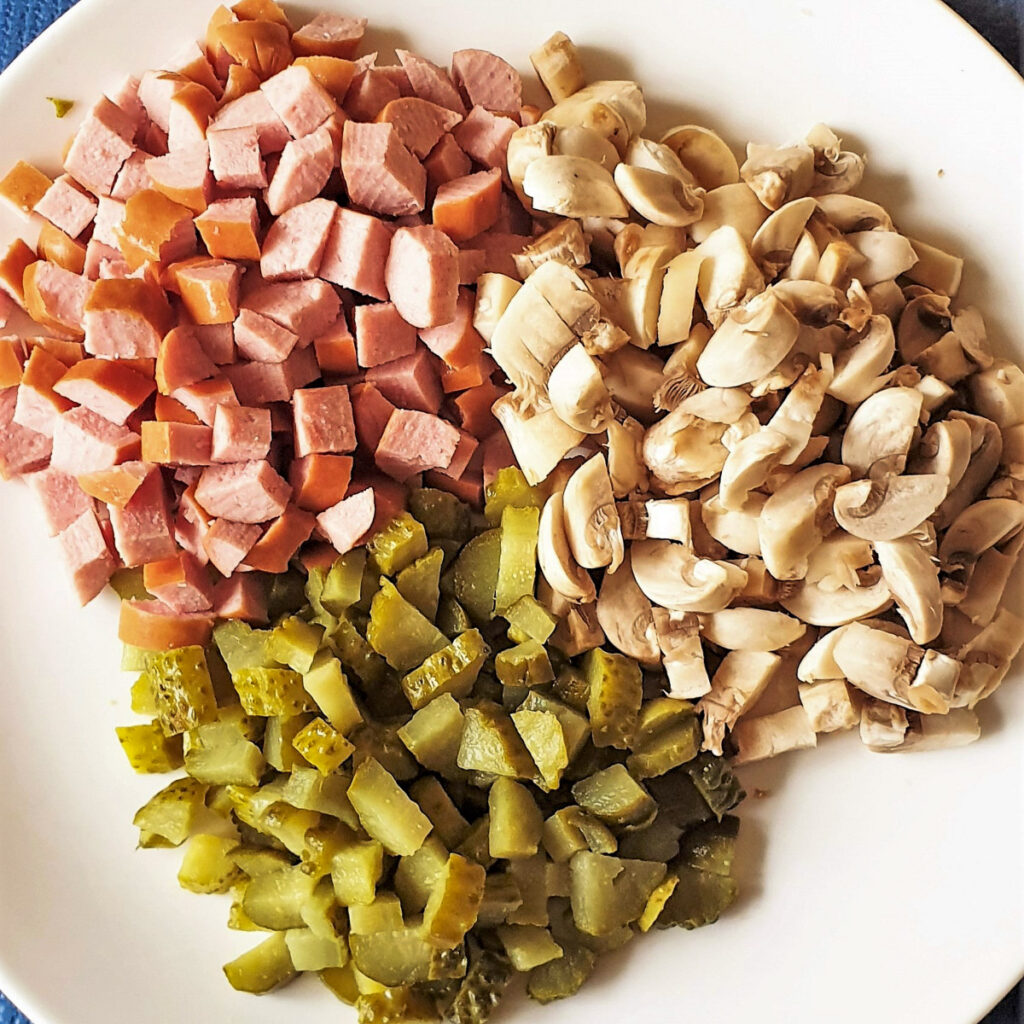 Chopped sausage, mushrooms and gherkins on a plate.