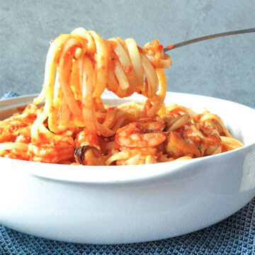 A forkful of linguine over a bowl of pasta pescatone.