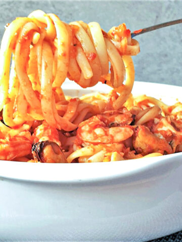 A forkful of linguine over a bowl of pasta pescatore.