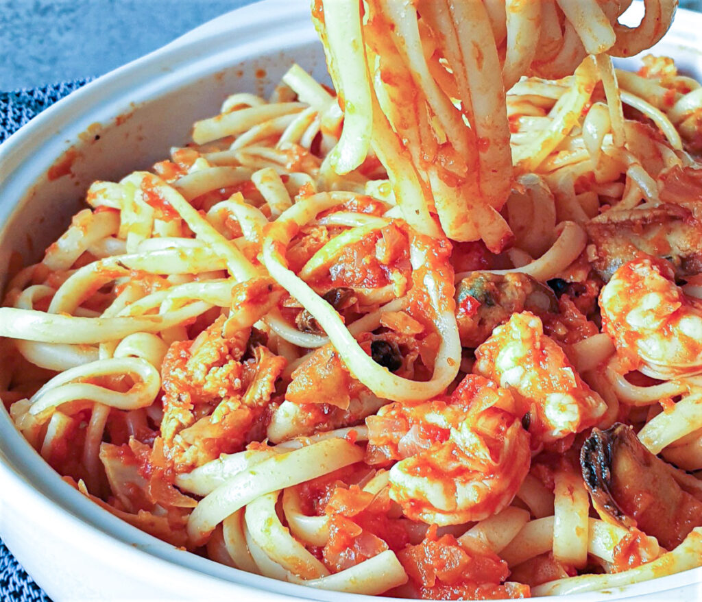 A forkful of linguine over a bowl of pasta pescatone.