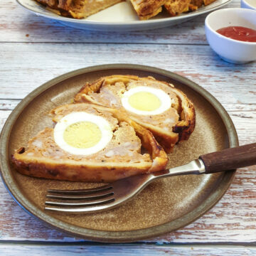 Two slices of sausage and egg picnic roll on a plate showing the egg on the inside.