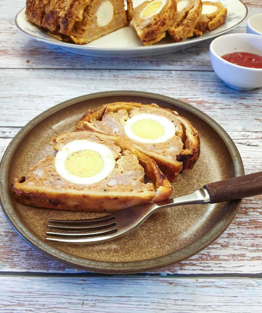 Two slices of sausage and egg picnic roll on a plate showing the egg on the inside.