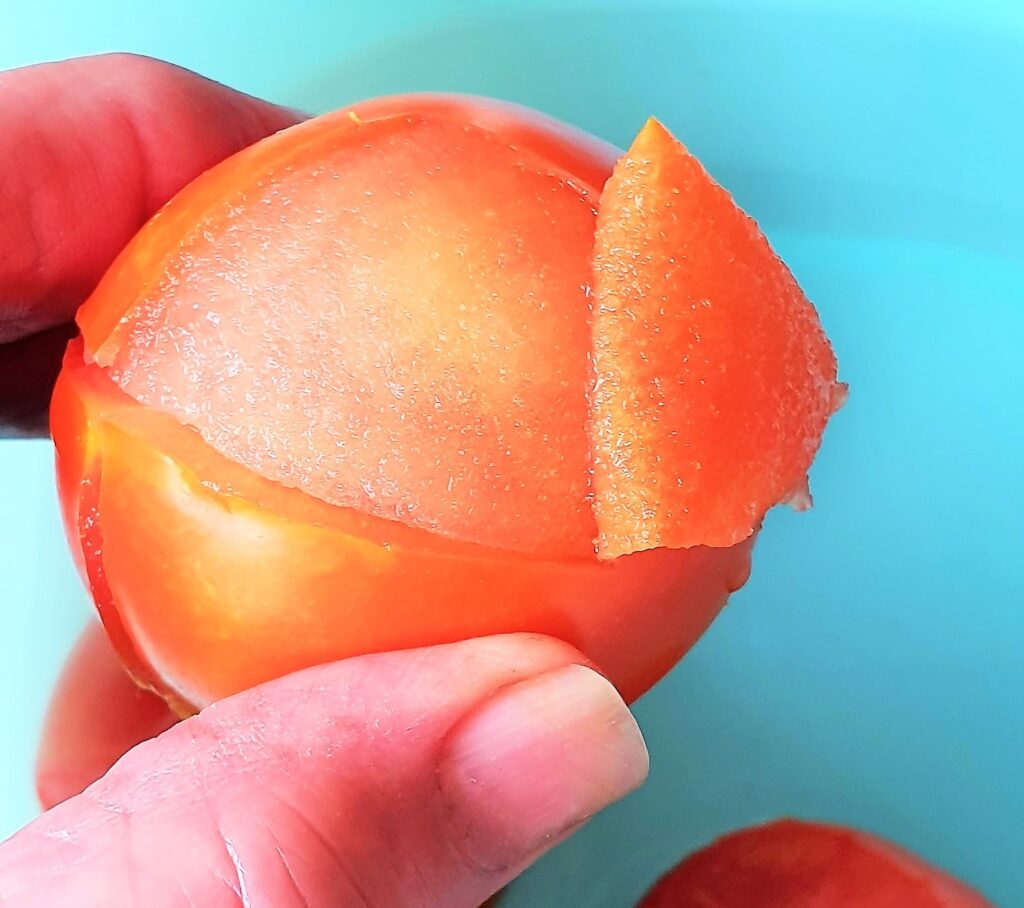 A tomato with the skin being peeled off.