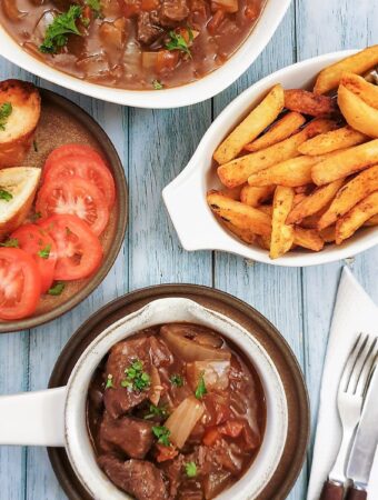 A dish of beef Trinchado alongside a bowl of french fries and garlic bread.