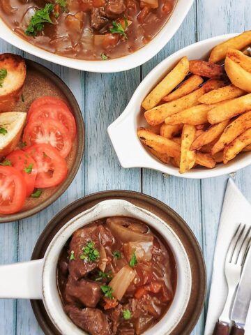 A dish of beef Trinchado alongside a bowl of french fries and garlic bread.