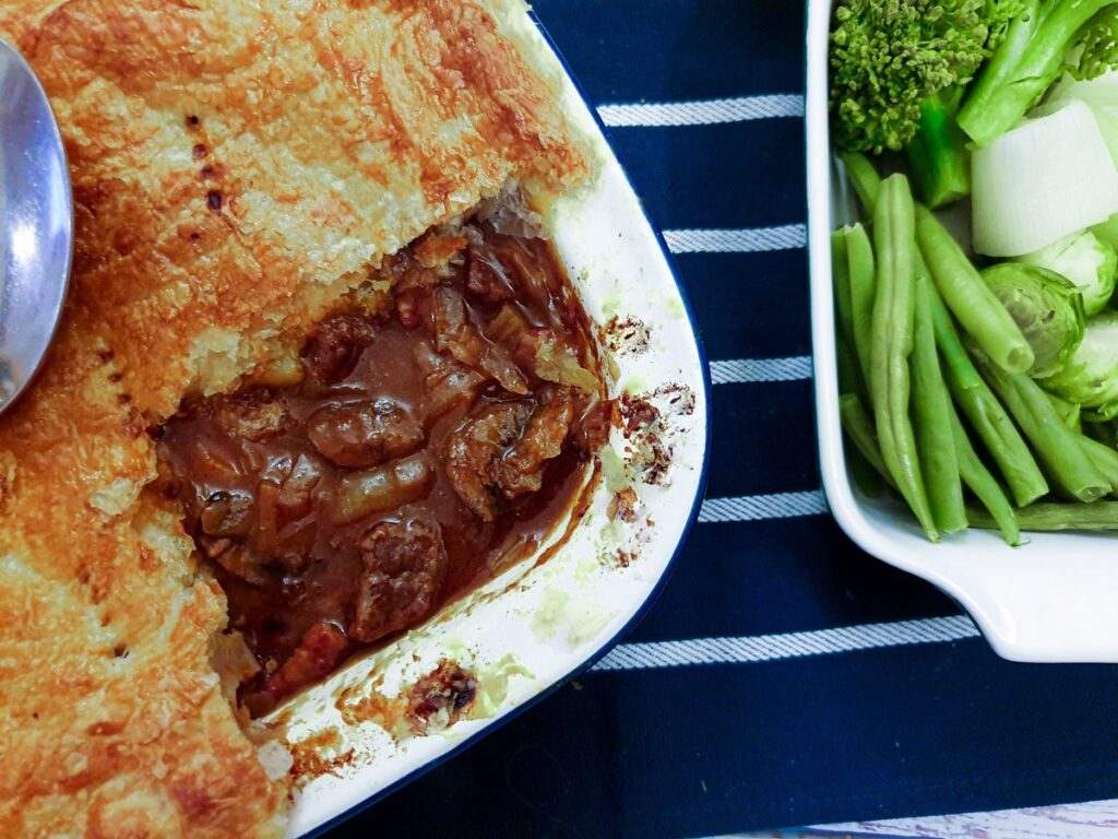 Beef and mushroom pie with the corner removed to show the filling.