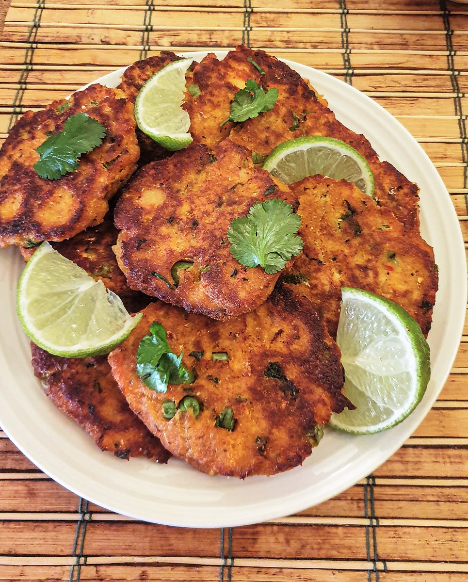 A plate of Thai salmon fishcakes garnished with slices of lime and coriander.