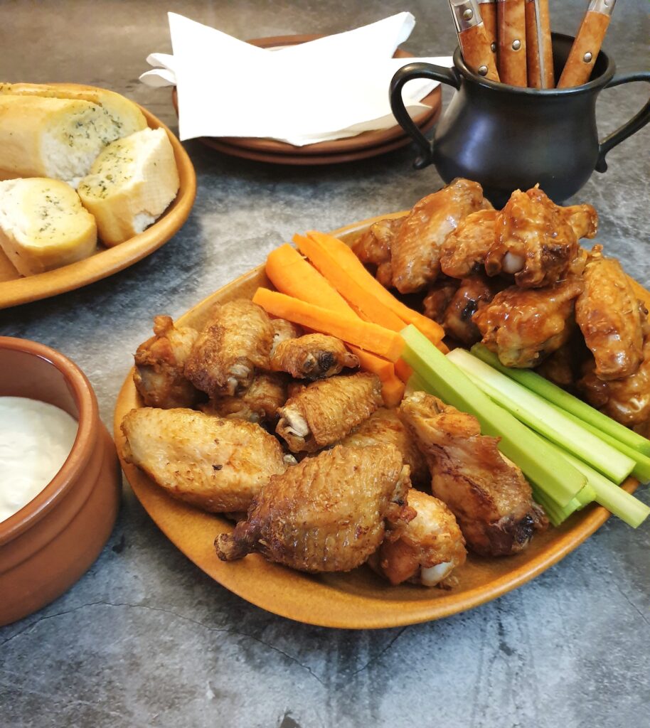 A piate of crispy air-fryer crispy chicken wings on a table with carrot and celery sticks.