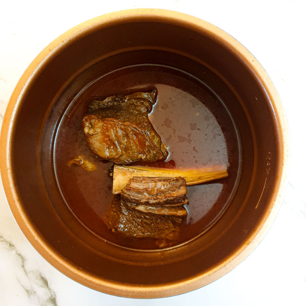 Two pieces of cooked short rib showing how the bone falls away from the meat.