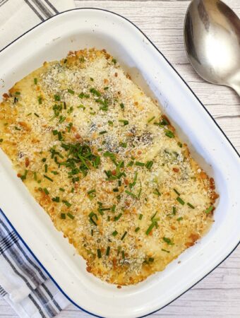 A dish of cauliflower and broccoli cheese sprinkled with chopped chives.
