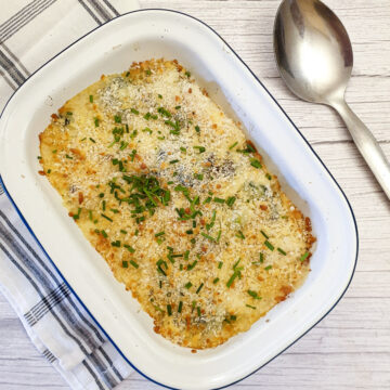 A dish of cauliflower and broccoli cheese sprinkled with chopped chives.