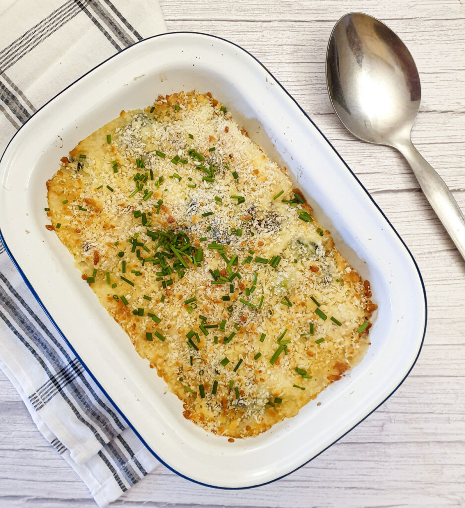 A dish of cauliflower and broccoli cheese sprinkled with chopped chives.