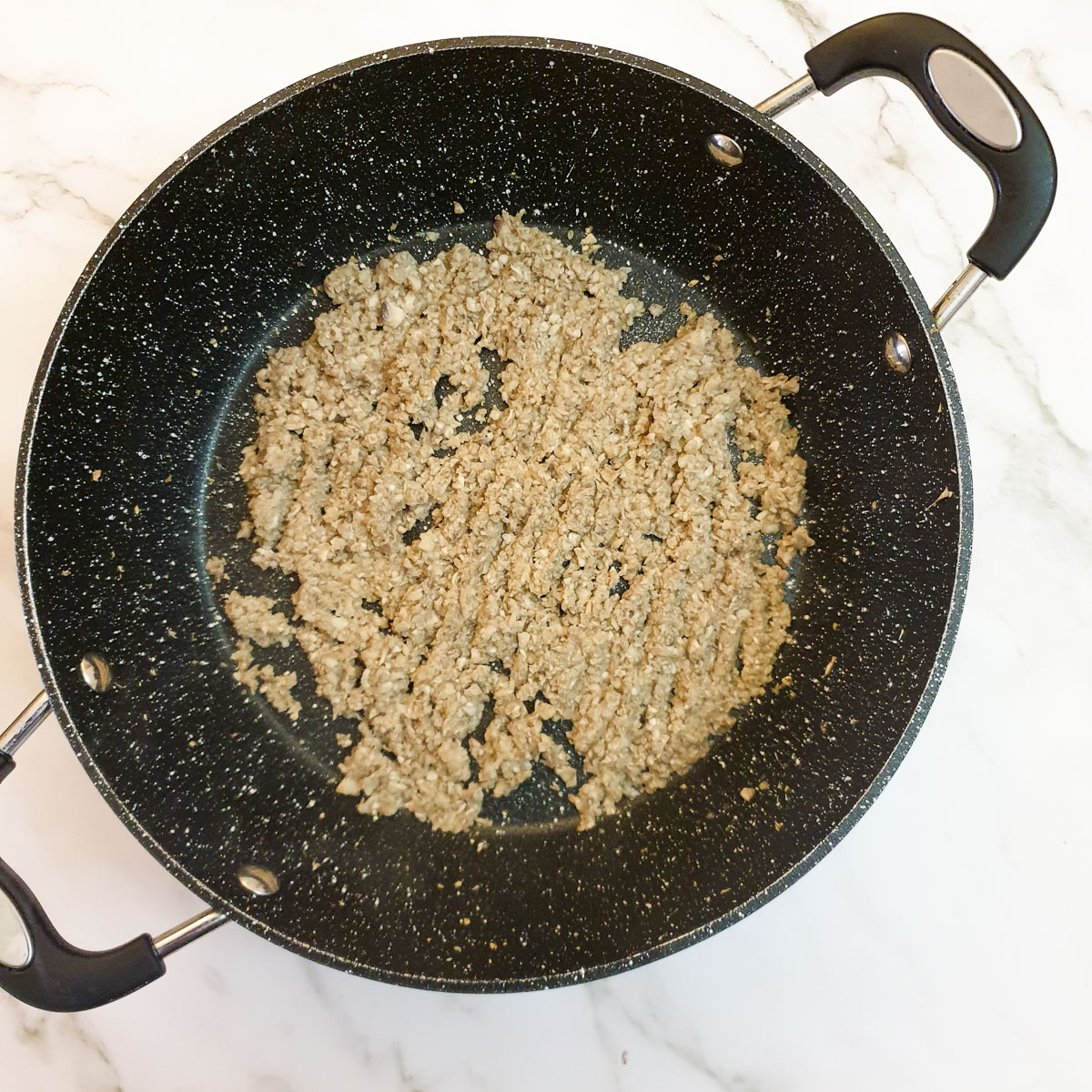 Finely chopped mushrooms frying in a frying pan.