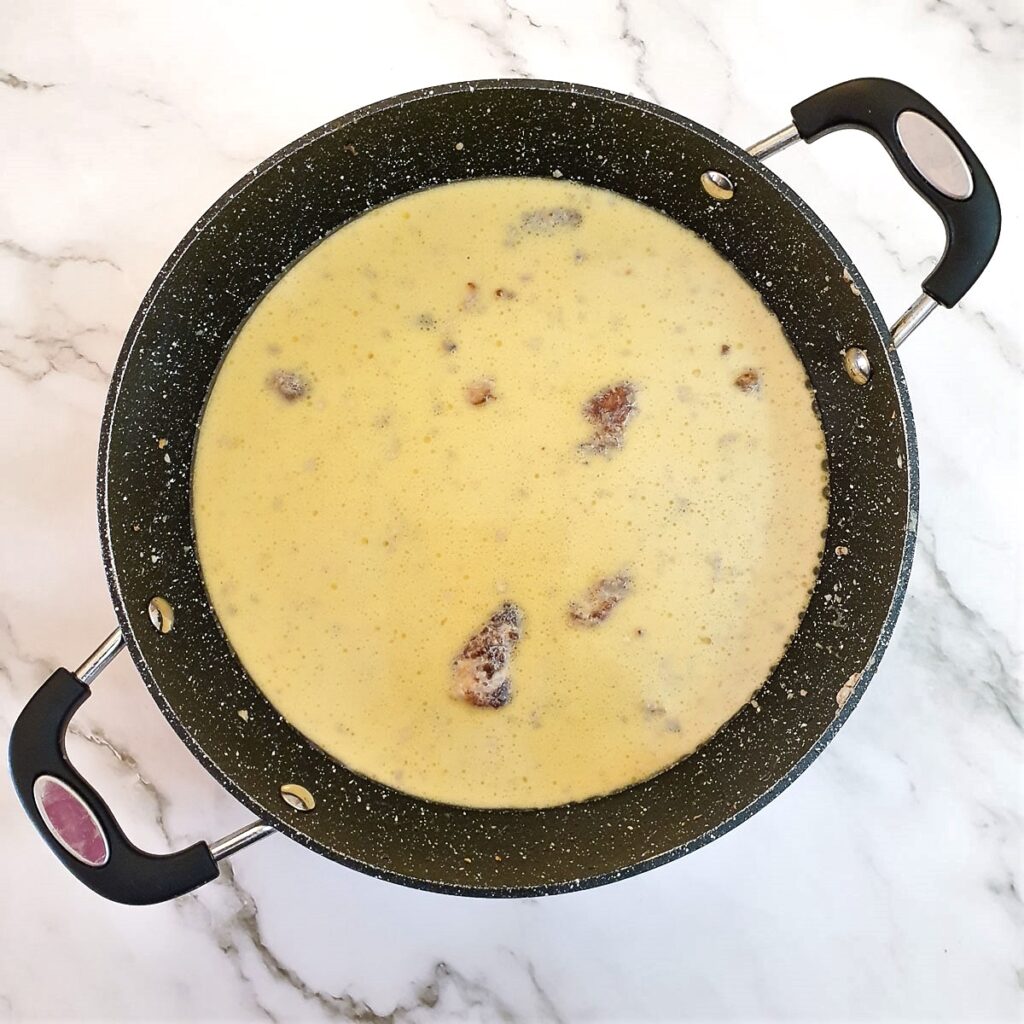 Chicken and mushrooms in a pan covered with milk.