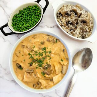 A dish of chicken Diane next to a bowl of peas and a dish of rice.