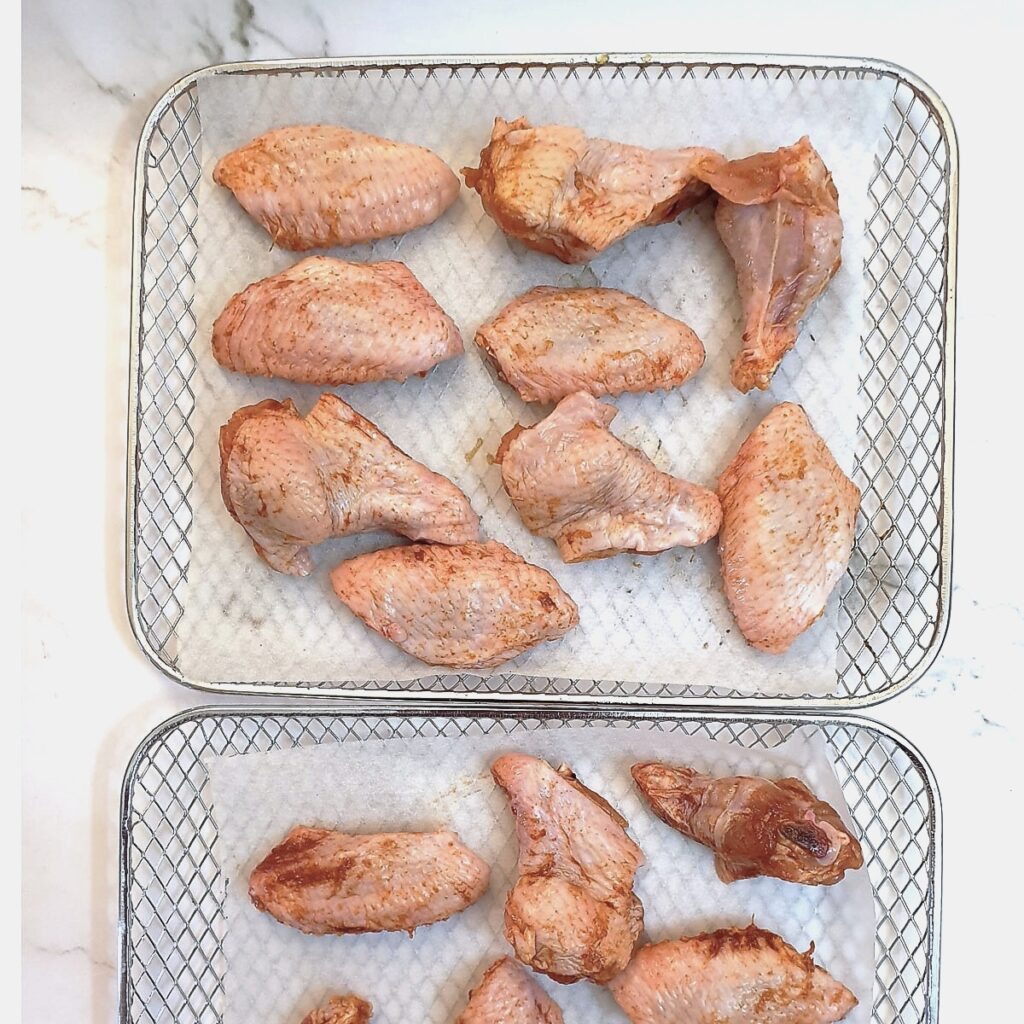Chicken wings arranged on trays ready to be air-fried.