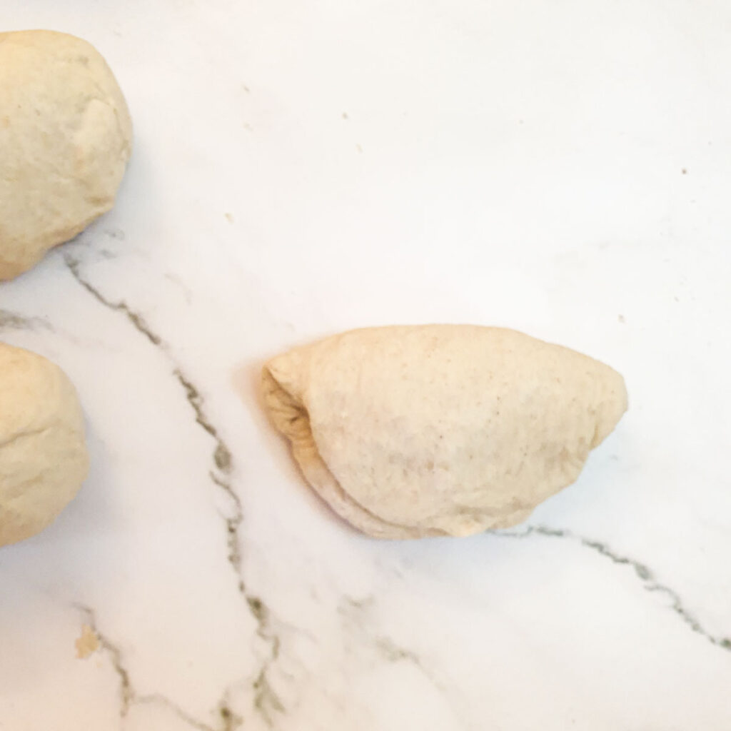 The flattened ball of dough folded in half.